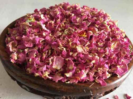 Wooden bowl filled with pink dried flowers on a light background