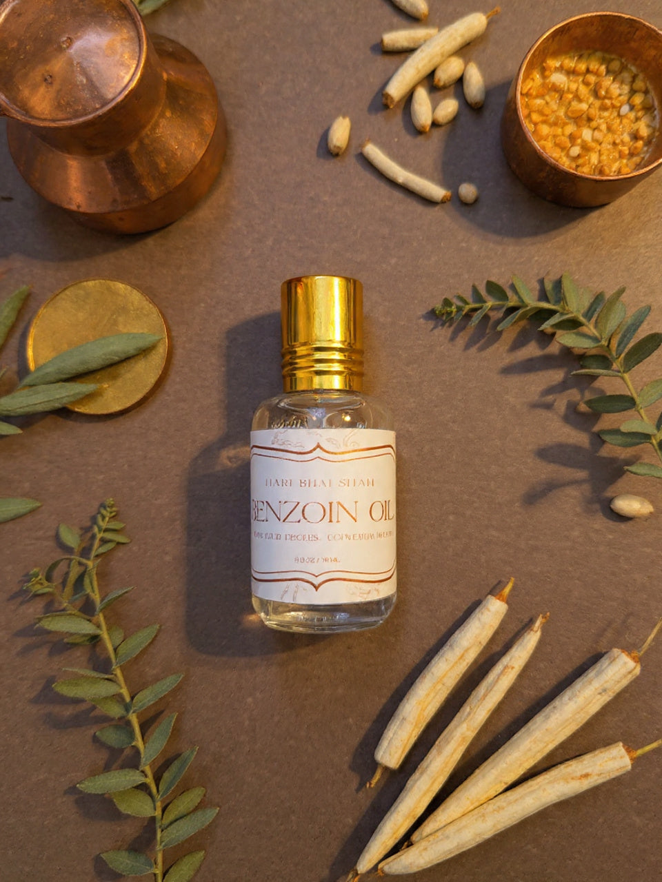 Bottle of Benzoin oil with dried benzoin resin and leaves on a brown background