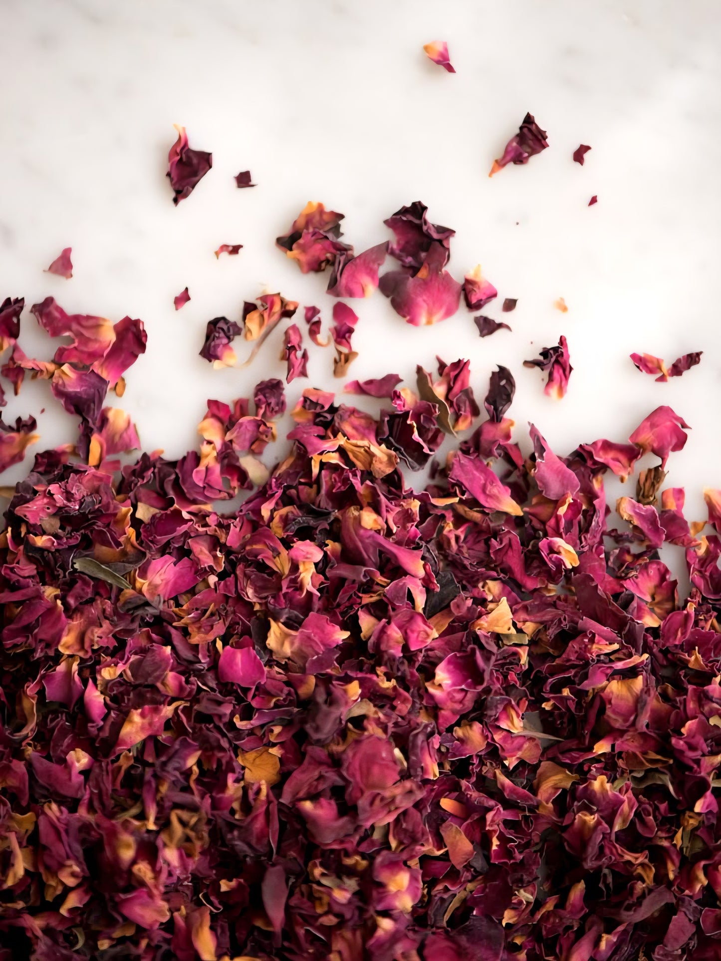 Dried pink and purple flower petals scattered on a white surface