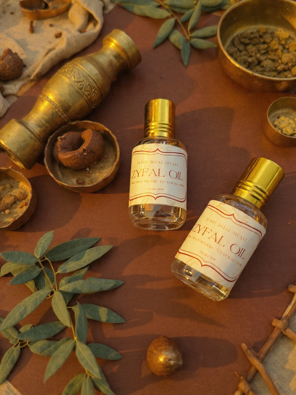 Two bottles of 'Zyfal Oil' on a brown surface with leaves and other items.
