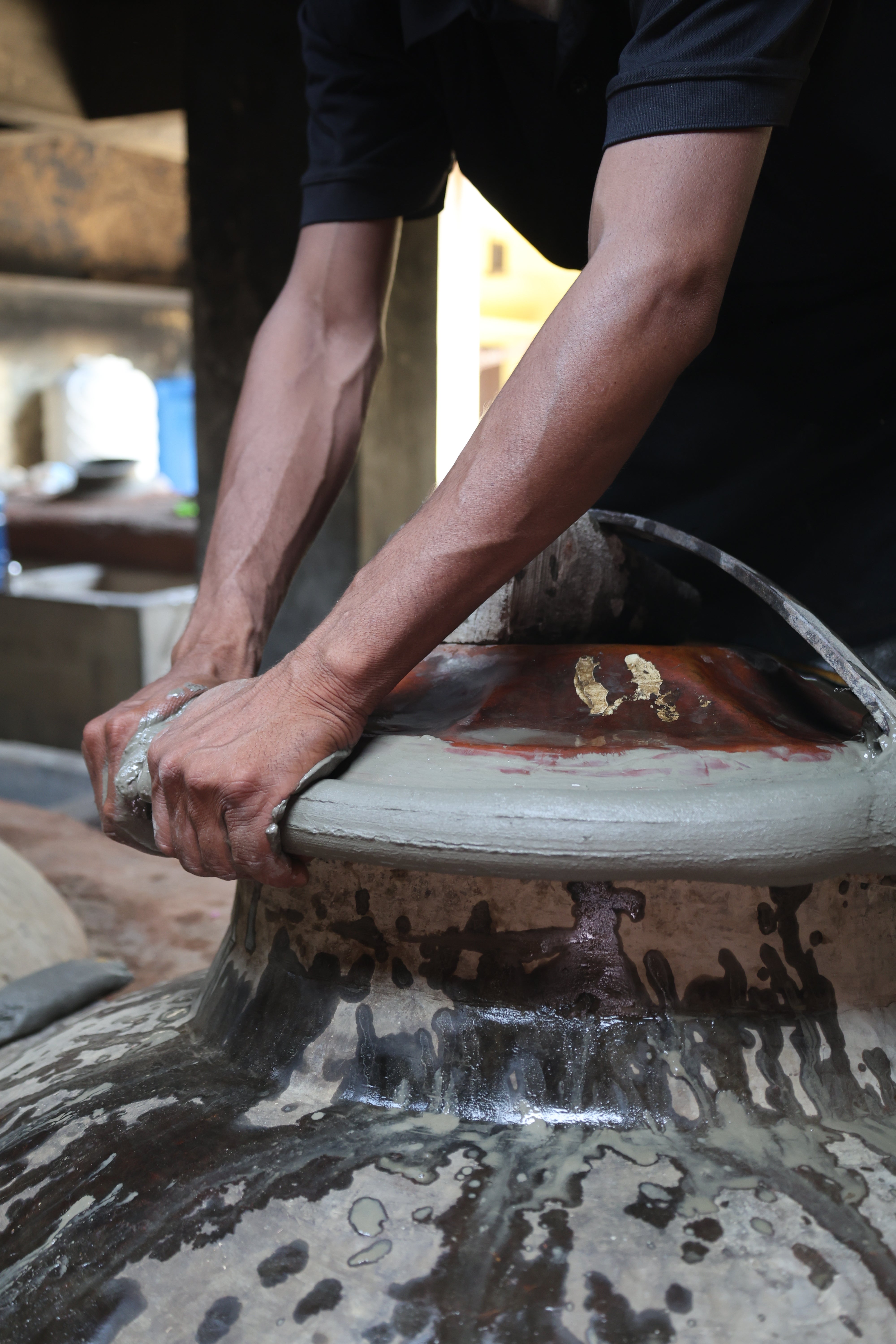 Hands sealing the copper deg with mitti clay — Hari Bhai Shah workshop, Kannauj